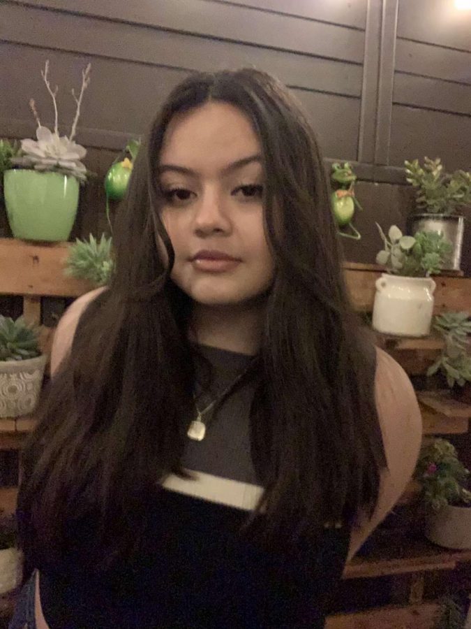 Alexa Perez taking a picture surrounded by beautiful plants and flowers. 