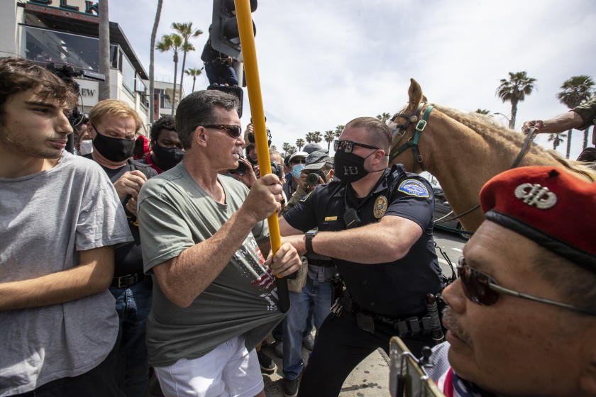 Police officer attempts to prevent violence. Photo courtesy of: Los Angeles Times.
