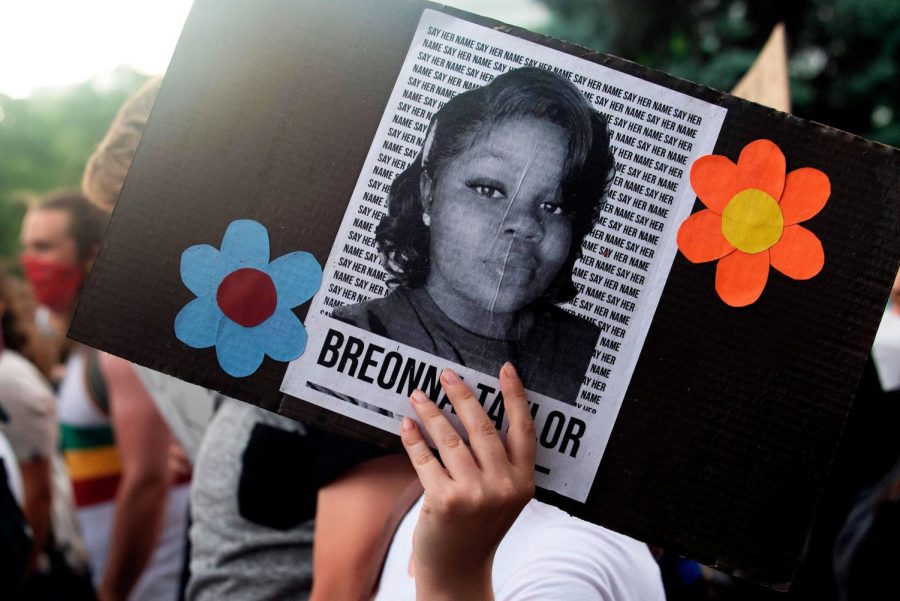 A protestor holds a sign with Breonna Taylors picture on it.