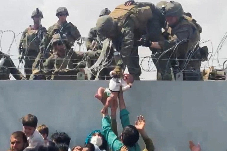 An Afghan civilian hands over 2-month old Sohail Ahmadi to an American soldier during the evacuation at the Kabul airport.