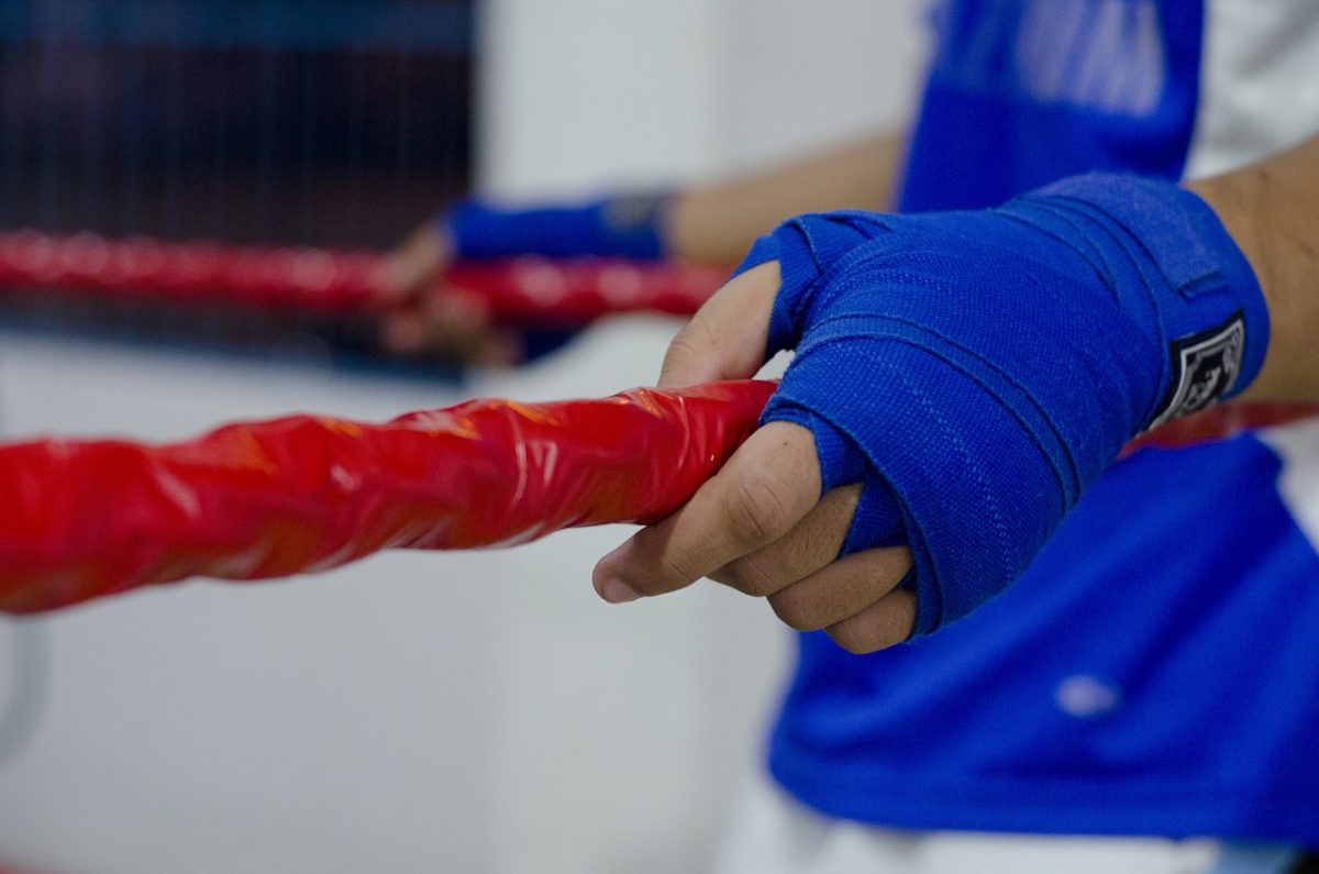 Image of a fighter grabbing the ropes in the corner of a boxing ring. Jake Paul and Anthony Joshua's future boxing match is highly anticipated by fans. 